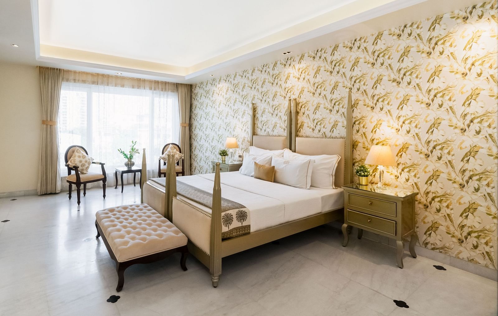A room at Dileep Kothi, Jaipur with a double bed, side tables with night lamps and a coffee table arrangement placed in front of French windows